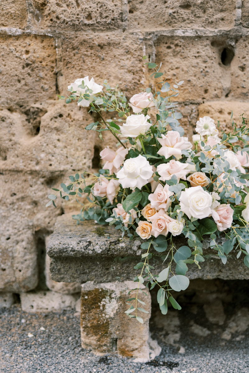 A blush and taupe wedding bouquet outside of a historic italy wedding venue